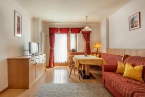 - un salon avec un canapé rouge et une table dans l'établissement Residence Angelika, à Corvara in Badia