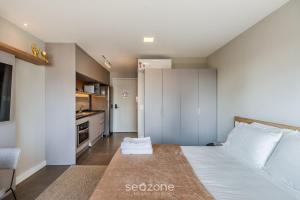 a bedroom with a white bed and a kitchen at Studio de Alto Padrão no Moinhos GOS1007 in Auxiliadora +15 photos