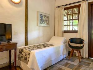 a bedroom with a bed and a tv and a chair at Pousada Vila Serrano in Lençóis