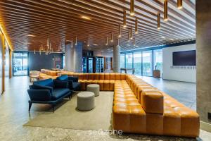 a lobby with a large leather couch and chairs at Studio de Alto Padrão no Moinhos GOS1007 in Auxiliadora