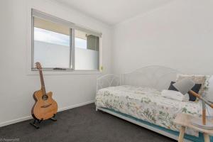 Un dormitorio con una cama y una guitarra. en Sunny Retreat in Kingston Beach, en Kingston Beach