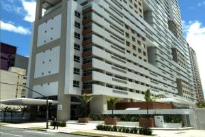a tall white building with a person walking in front of it at Espaço especial IX in Curitiba