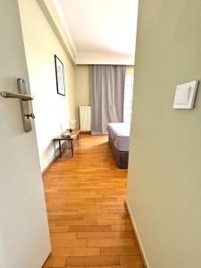 a room with a bed and a wooden floor at Comfort and Sunny Apartment, Marousi OAKA Stadium Neratziotissa in Athens