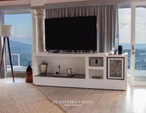 a living room with a flat screen tv on a white entertainment center at Hotel Boutique de Cantera Y Plata in Taxco de Alarcón