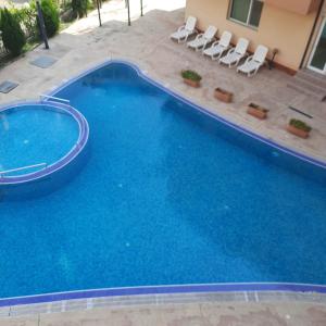 a large blue swimming pool with white chairs in it at Studio Apartment with Pool View, Sunny Beach in Sunny Beach