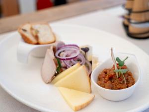 a white plate with a bowl of food with cheese and bread at Casa Din Bran - Inn Cuisine in Bran