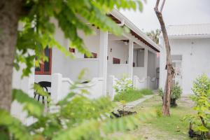 a white house with a tree in front of it at Velidhoo Inn in Velidhoo