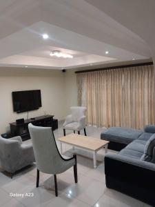 a living room with a couch and chairs and a tv at CozyNest in Margate