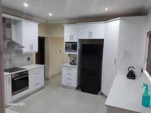 a kitchen with white cabinets and a black refrigerator at CozyNest in Margate +1 photo