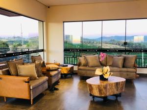 a living room with couches and tables and large windows at Vinícola e Hospedaria Bonventi Ltda in Espirito Santo Do Pinhal