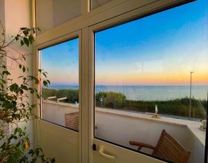 a door with a view of the ocean from a balcony at LA PERLA BIANCA Apartment - Near Train Station and Best Beaches with Amazing Sunsets in Anzio