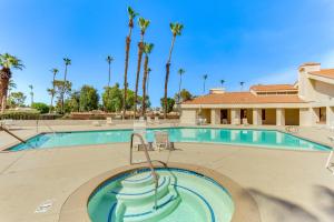 a swimming pool with palm trees in the background at Golf, Hike and Relax Cathedral City Condo in Cathedral City