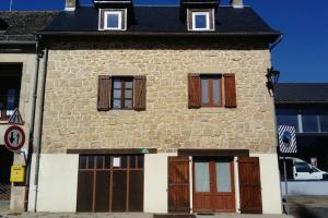 a stone building with brown doors and windows at Maison au cœur d'un petit village in Goutrens
