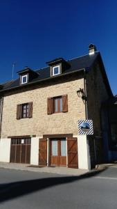 a large brick building with doors and a black roof at Maison au cœur d'un petit village in Goutrens
