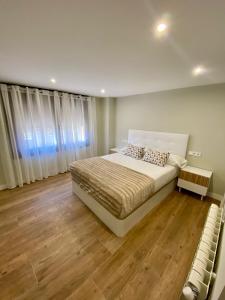 ein Schlafzimmer mit einem großen Bett und Holzböden in der Unterkunft Villa Maca in Pontevedra