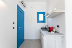 a kitchen with white walls and a blue door at Corfos Pearl Studios in Ornos