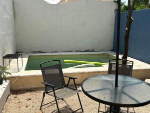 two chairs and a table and a pool with baseball bats at Casa Ufemia in Mérida +5 photos