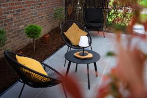 a patio with two chairs and a table with a lamp at Le Cocon de Jeanne in Hannut