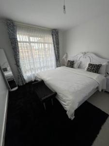 a bedroom with a large white bed and a window at The O Apartment in Ongata Rongai 
