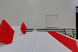 einem roten und weißen Bett mit roten Kissen darauf in der Unterkunft Hotel O Shyam Residency in Rewāri