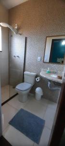 a bathroom with a toilet and a sink and a mirror at Alvorada Guest House in Caxambu