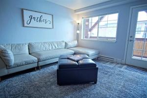 a living room with a couch and a ottoman at Game Room, Heated Pool, Hot Tubs, Private Washer Dryer in Steamboat Springs