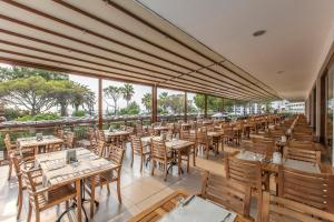 an empty restaurant with wooden tables and chairs at Atlantique Holiday Club - All Inclusive in Kuşadası