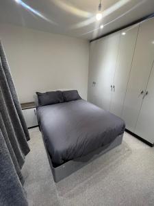 a bedroom with a bed and white cabinets at This Stylish Apartment Is Perfect Near Greenwich in Eltham