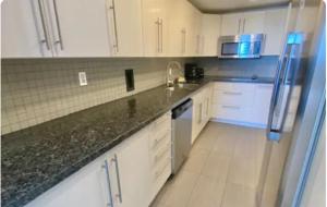 a kitchen with white cabinets and a black counter top at Miami Hollywood High Rise Condo 004-22bvic in Hollywood