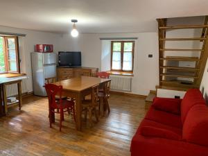 ein Wohnzimmer mit einem Tisch und einem roten Sofa in der Unterkunft Lu Biulè Ca' d'Aldo in Groscavallo