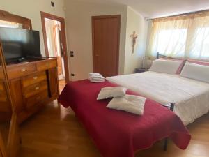 a bedroom with a bed with a red blanket and a tv at Villa Radiosa in Gravina in Puglia
