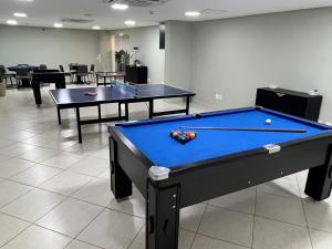 two ping pong tables sitting in a room with a pool table at Apartamento Parque do Peão in Barretos