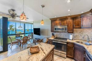 a kitchen with wooden cabinets and a table with chairs at KS507 Spectacular Oceanfront with Split AC Wailea in Wailea