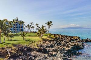 a view of a resort with palm trees and the ocean at KS507 Spectacular Oceanfront with Split AC Wailea in Wailea