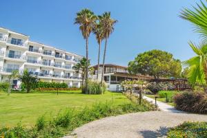 a large hotel with palm trees and a park at Atlantique Holiday Club - All Inclusive in Kuşadası
