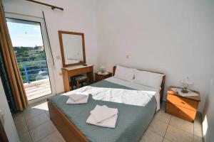 a bedroom with a bed with a mirror and a window at Long Beach Koutsounari in Ierápetra