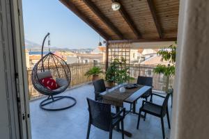 a balcony with a table and chairs and a swing at Evelina 5 in Lixouri