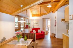 a living room with a red couch and wooden ceilings at Obergostnerhof in Chiusa +18 photos