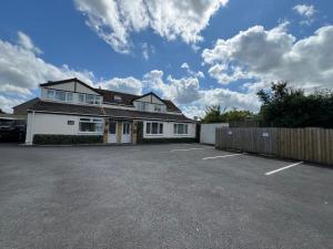 a white house with a fence and a parking lot at Edge of Glastonbury and Street - Large Ground Floor 3 BD With Parking, 4 Single and 1 Double Bed in Street