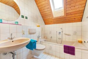 een badkamer met een wastafel, een toilet en een bad bij Decker's Bio Hotel zum Lamm in Baiersbronn
