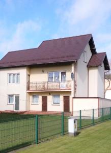 a large white house with a fence at Pokoje Mariola in Karwia