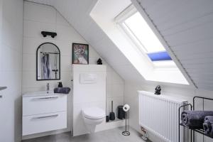 a white bathroom with a toilet and a skylight at Ferienwohnung 12 Monkeys in Stuhr +50 photos