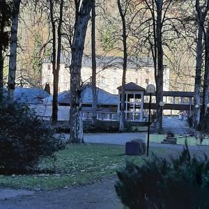 a building in the middle of a park with trees at Studio relooké Le Grand Tétras 2 étoiles in Aulus-les-Bains