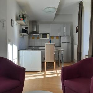 a kitchen with white cabinets and a table and chairs at Studio relooké Le Grand Tétras 2 étoiles in Aulus-les-Bains +12 photos