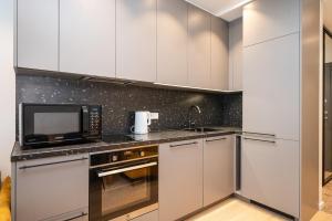 a kitchen with white cabinets and a microwave at Scandinavian style apartment in Vilnius +15 photos