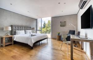 Un dormitorio con una cama, un escritorio y un televisor. en AR 218 Hotel by ULIV, en Ciudad de México