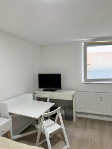 a white office with a desk and a computer monitor at Möbliertes Zimmer in Villingen-Schwenningen