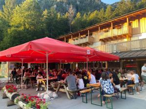 un gruppo di persone seduti ai tavoli sotto un ombrello rosso di Rifugio Pian dei Ciclamini a Lusevera