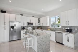 Una cocina con gabinetes blancos y electrodomésticos de acero inoxidable. en Endless Summer Key Largo House, en Cayo Largo