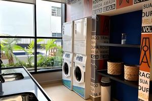 a laundry room with a washer and dryer next to a window at Zyz Centro in Sao Paulo